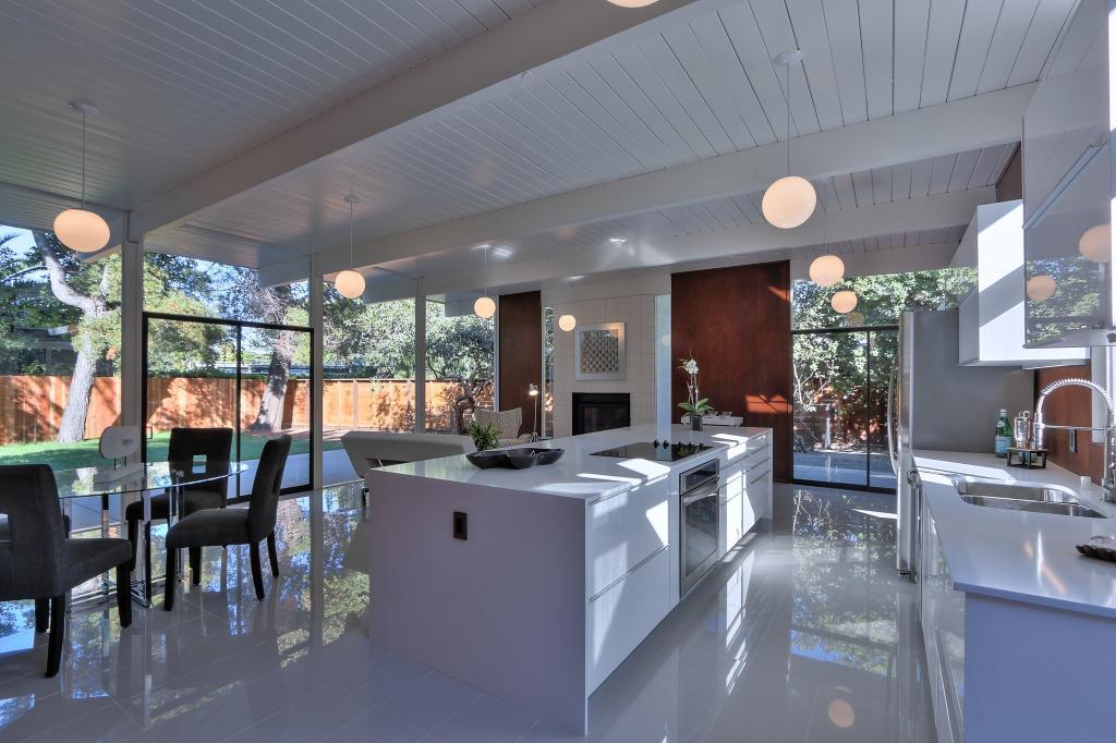 Eichler kitchen with white island, globe pendant lights, and open glass walls