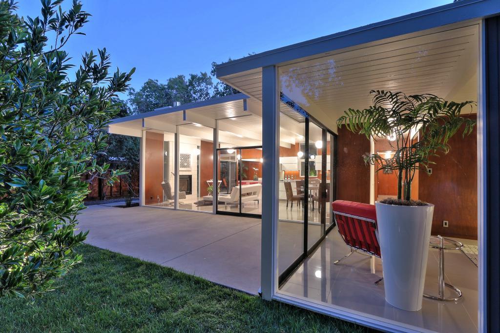 Eichler patio with glass walls and modern interior visible at dusk